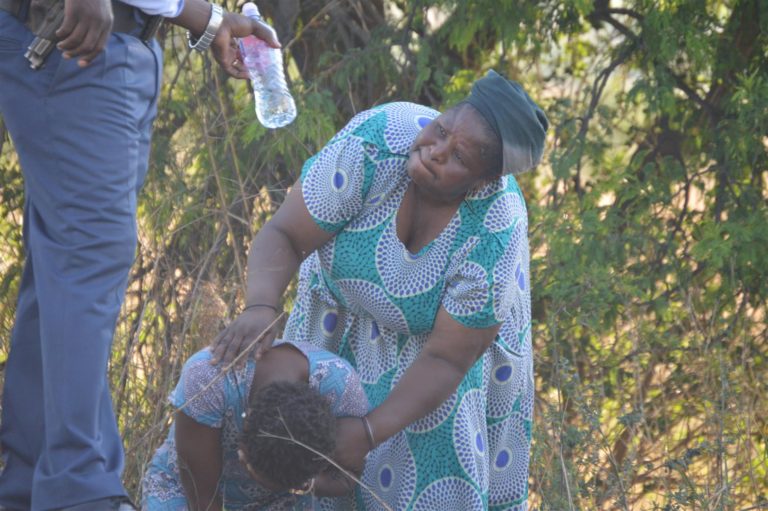 A compassionate police officer hands a grieving family member a bottle of water 