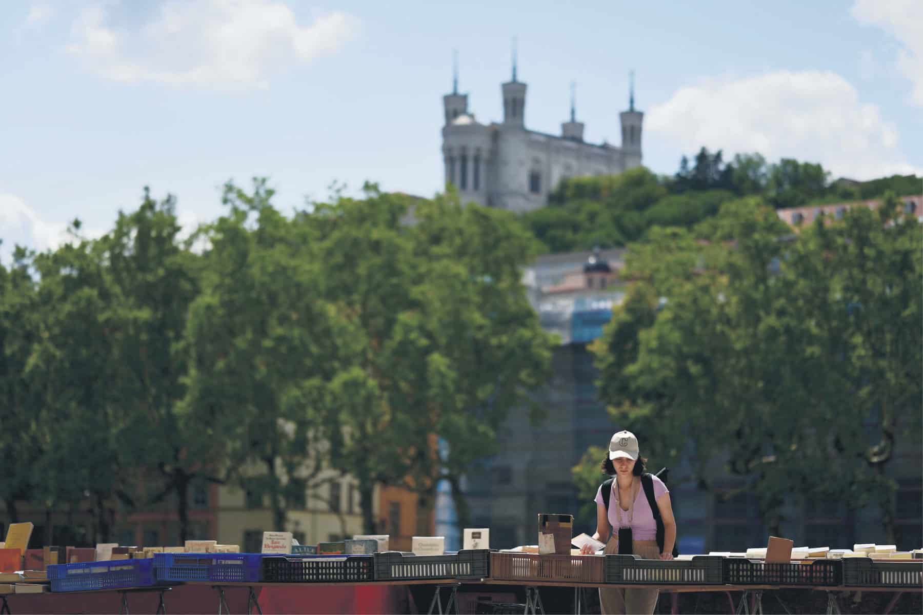 CENTURIES-OLD. A woman looks at books along the Saone river embankments in front of the Notre-Dame de Fourviere basilica in Lyon. Picture: AFP