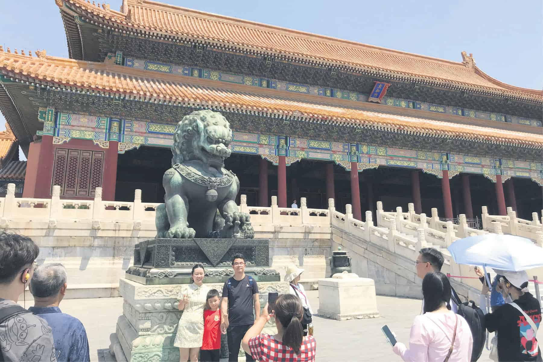 READY. A family poses for a picture in front of a statue of a female lion at the Gate of Supreme Harmony in the Palace Museum, Beijing. Picture: Amanda Watson