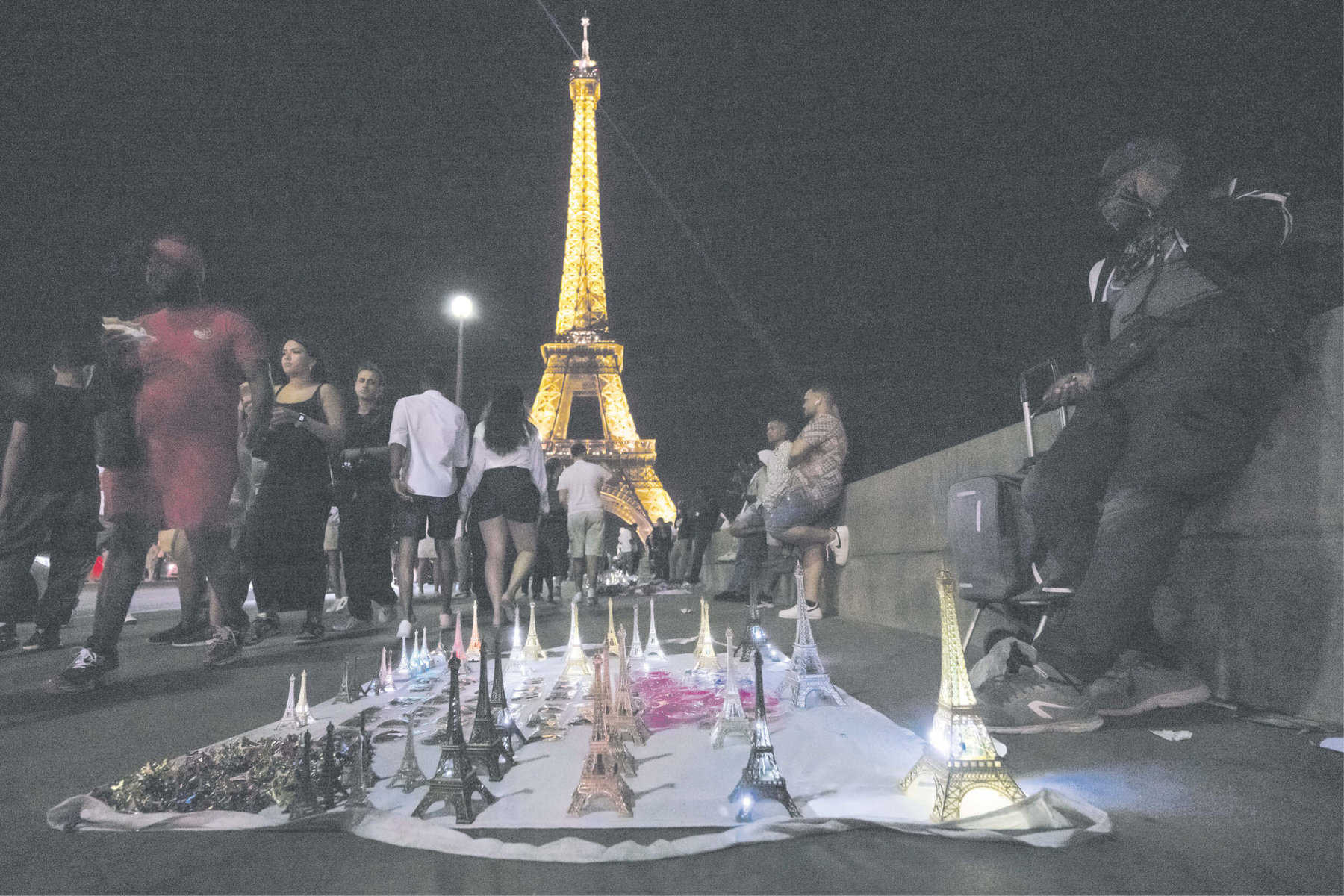 COMPLETED IN 1889: Tourists walk past street vendors selling souvenirs
by the Eiffel Tower in Paris. Picture: AFP